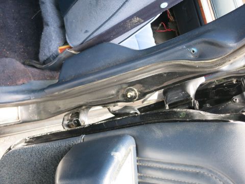 1991 Ford LTD Crown Victoria - Detail of a car's B-pillar, door striker and seat-belt area framed by blue interior trim.
