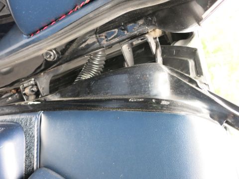 1991 Ford LTD Crown Victoria - Detail of a car door hinge area showing a coiled spring, wiring loom and blue interior trim.