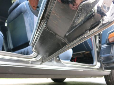 1991 Ford LTD Crown Victoria - Low-angle close-up of a black car's lower door edge and chrome rocker trim with blue seat visible inside.