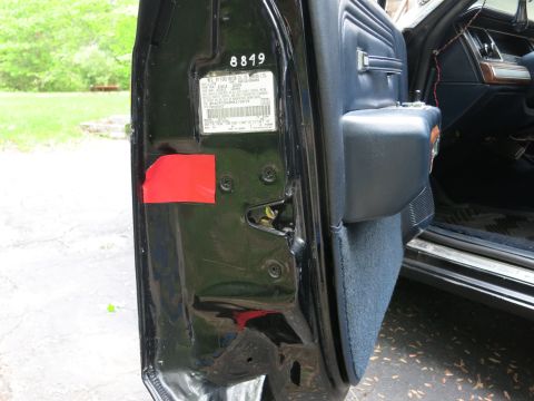 1991 Ford LTD Crown Victoria - Inner door jamb of a black car showing a printed VIN/spec label, red tape and the navy door panel.