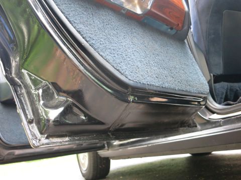 1991 Ford LTD Crown Victoria - Detail of an open black car door showing the blue carpeted floor, door sill and lower trim.