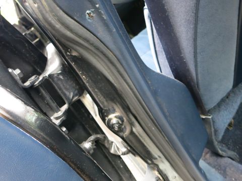 1991 Ford LTD Crown Victoria - Close-up of a black car's door hinge and chrome latch hardware against a blue cloth interior.