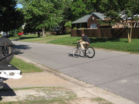 1994 Ford Bronco - A person rides a bicycle down a residential street on a sunny day.