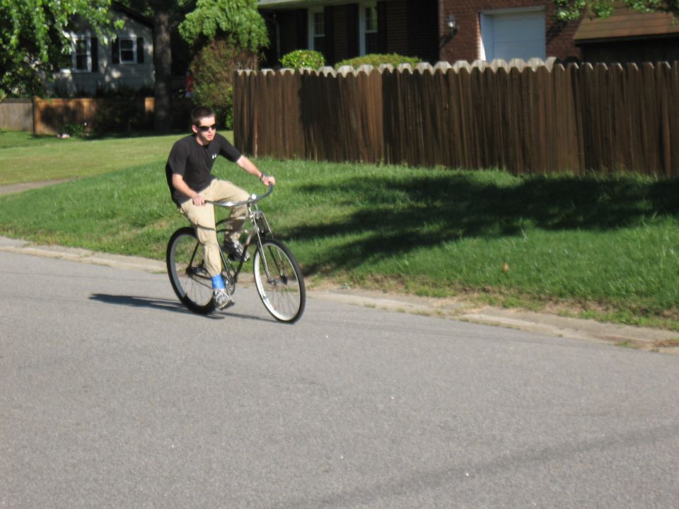 Man riding a motorized bicycle on a suburban street