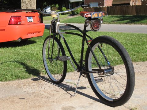 1994 Ford Bronco - A custom bicycle is parked next to the rear of an orange Ford Mustang.