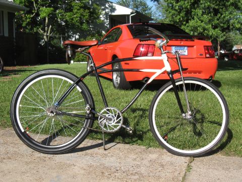 1994 Ford Bronco - A custom bicycle is parked in front of a red Ford Mustang.