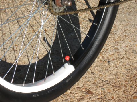1994 Ford Bronco - Close-up of a bicycle wheel with a red valve cap against a concrete background.