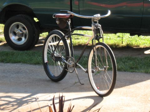 1994 Ford Bronco - A cruiser bicycle is parked on a concrete driveway next to a green truck.