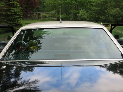 1991 Ford LTD Crown Victoria - Front windshield of a black car with a white roof, showing a whip antenna and small red and amber dash lights inside.