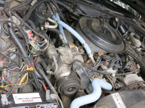 1991 Ford LTD Crown Victoria - Close-up of an engine bay with blue hoses, colorful wiring, a Bosch battery and a round air cleaner.