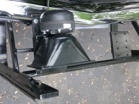 1991 Ford LTD Crown Victoria - black siren or PA speaker mounted on a steel bracket behind a vehicle's front grille over cracked asphalt.