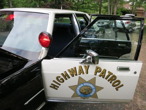 1991 Ford LTD Crown Victoria - Open white car door lettered HIGHWAY PATROL with a California Highway Patrol star-shield badge and red dome light above.