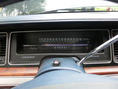 1991 Ford LTD Crown Victoria - Close-up of a horizontal-sweep speedometer marked to 140 mph with a column-shift gear indicator on a blue dashboard.