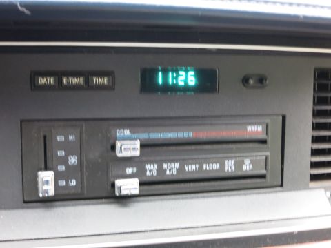 1991 Ford LTD Crown Victoria - Center dash climate-control panel with sliding fan and temperature levers and a green digital clock showing 11:26.