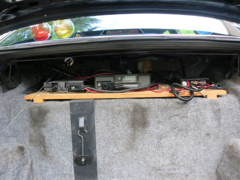 1991 Ford LTD Crown Victoria - Open vehicle trunk fitted with a wooden platform holding mounted two-way radio gear, wiring and an antenna lead.