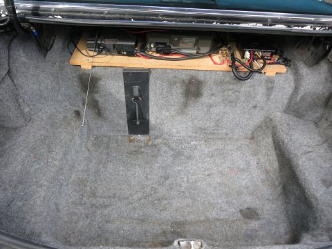 1991 Ford LTD Crown Victoria - Wide view of a carpeted car trunk with two-way radio equipment and wiring mounted on a raised wooden shelf.
