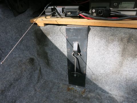 1991 Ford LTD Crown Victoria - Interior of a car trunk showing an antenna whip, a black metal mounting bracket and radio gear above gray carpet.