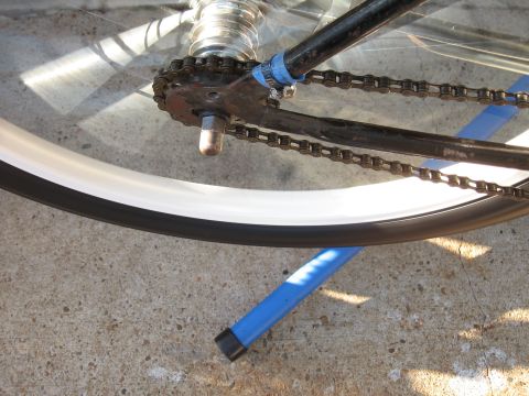 1994 Ford Bronco - Bicycle chain and wheel detail, resting on a blue stand on concrete.