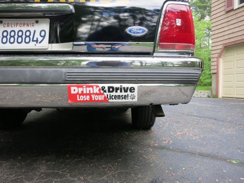 1991 Ford LTD Crown Victoria - Rear bumper of a black Ford showing California plate 888849 and a red Drink & Drive Lose Your License bumper sticker.