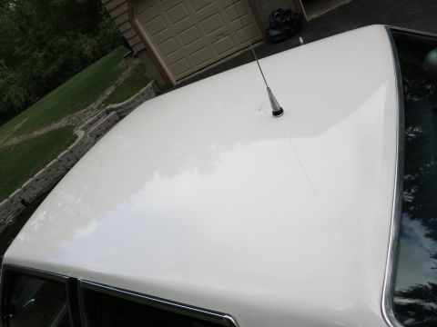 1991 Ford LTD Crown Victoria - White painted car roof with a chrome-based whip antenna mounted at center, a garage and landscaped yard behind.