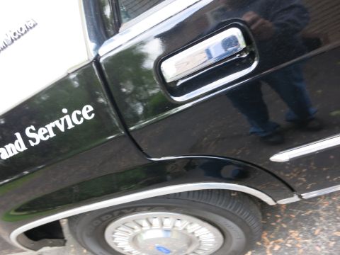1991 Ford LTD Crown Victoria - Black car front fender with a chrome door handle, white 'and Service' lettering and a Ford-logo wheel cover.
