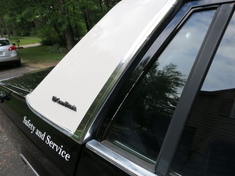 1991 Ford LTD Crown Victoria - Two-tone Grand Marquis sedan C-pillar and rear window showing the 'Grand Marquis' badge and 'Safety and Service' door lettering.