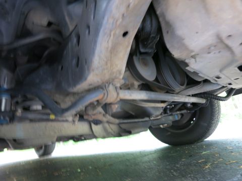 1991 Ford LTD Crown Victoria - Undercarriage view of a vehicle's front suspension showing a sway bar, drive belt and engine bottom components.