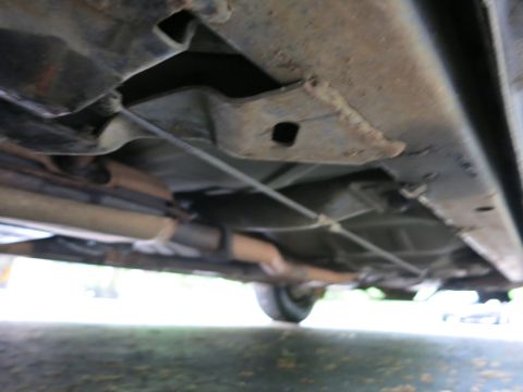 1991 Ford LTD Crown Victoria - Undercarriage view showing the stamped floor pan, frame rail and exhaust pipe of a vehicle over pavement.
