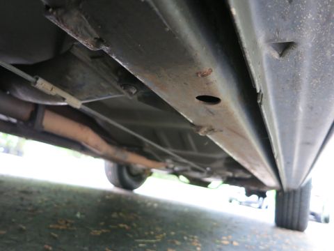 1991 Ford LTD Crown Victoria - Underside view along a vehicle's rocker panel and floor pan with an exhaust pipe and tire tread at right.