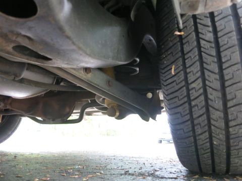 1991 Ford LTD Crown Victoria - Undercarriage view of a vehicle's rear suspension and exhaust pipe alongside a deep-tread rear tire.