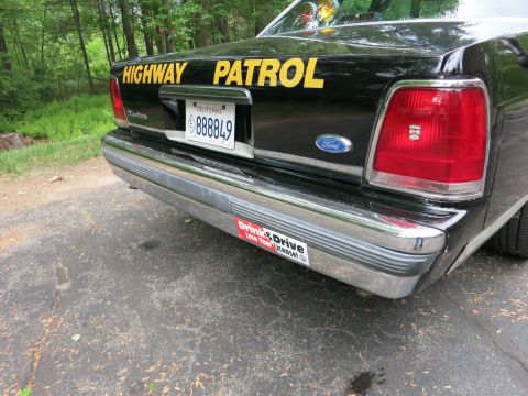1991 Ford LTD Crown Victoria - Rear of a black police sedan lettered 'Highway Patrol' with a Ford trunk badge, California plate and 'Drink & Drive' bumper sticker.