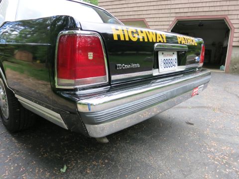 1991 Ford LTD Crown Victoria - Rear of a black police car wearing an 'LTD Crown Victoria' badge, yellow 'Highway Patrol' lettering and a California plate.