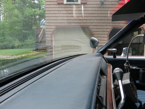 1991 Ford LTD Crown Victoria - Interior view over the dark dashboard and through the windshield of a car, looking out at a shingled house with a garage.