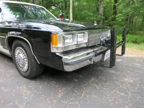 1991 Ford LTD Crown Victoria - Front corner of a black-and-white police car with stacked rectangular headlights, chrome bumper and a black steel push bar.