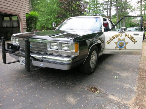 1991 Ford LTD Crown Victoria - Front three-quarter view of a black-and-white California Highway Patrol Ford police sedan with steel push bar and door-mounted spotlights.