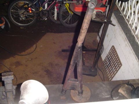 1993 Ford Bronco - A tall shop-built steel stand made from pipe and angle legs on a round base plate, standing on a garage floor. A bench vise and workbench e…