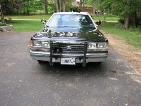 1991 Ford LTD Crown Victoria - Head-on front view of a black sedan showing a Ford grille emblem, chrome push bumper, and a California license plate reading 888849.