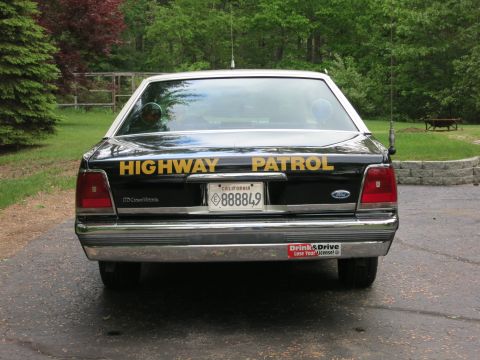 1991 Ford LTD Crown Victoria - Rear view of a black Ford Crown Victoria police cruiser with yellow Highway Patrol lettering and California plate 888849, parked on pavemen…
