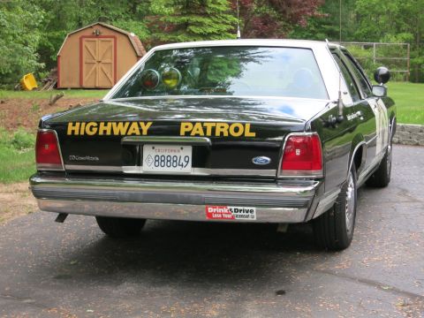 1991 Ford LTD Crown Victoria - Rear three-quarter view of a black Ford Crown Victoria police cruiser with yellow Highway Patrol lettering and California plate 888849.