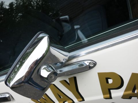 1991 Ford LTD Crown Victoria - Close-up of a chrome A-pillar spotlight and chrome door handle on a white car door bearing partial gold 'WAY PA' lettering.