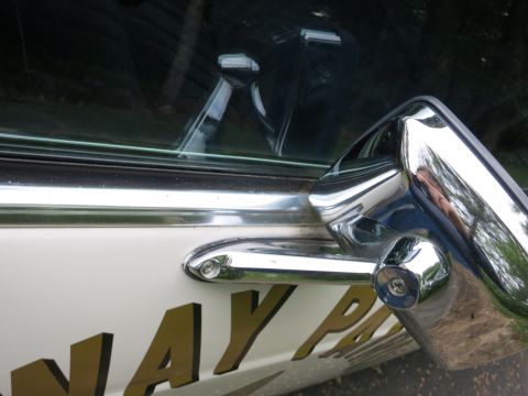 1991 Ford LTD Crown Victoria - Close-up of a chrome pillar-mounted spotlight and door handle on a white car door showing partial gold 'NAY P' lettering.