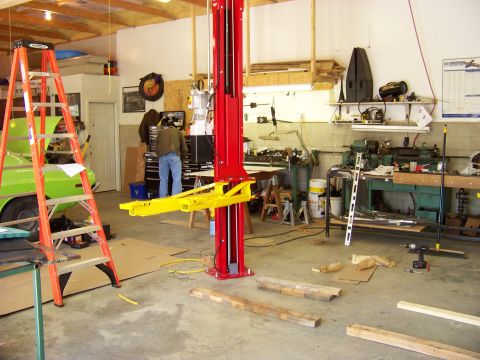 1974 Dodge Challenger - A green muscle car from the 1970s is parked in a garage next to a car lift and an orange ladder.
