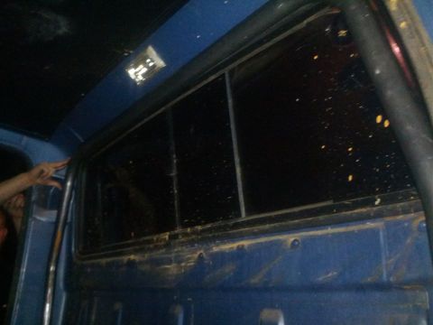 1979 Ford F-150 - The interior of a blue truck cab shows the rear window and a hand near the frame.