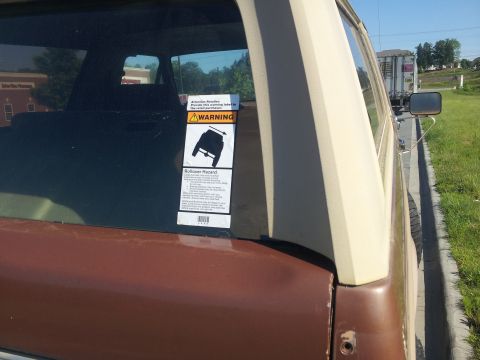 1988 Ford Bronco - A rollover hazard sticker is affixed to the rear window of this SUV, which is parked on the side of a road.