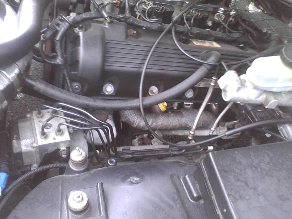 Close-up view of a car's engine bay, showing the engine block, hoses, and wiring