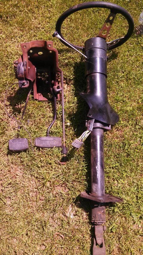 1979 Ford Bronco - Steering column and pedals are laid out on a grassy surface.