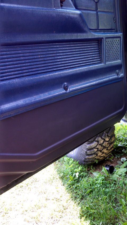 1979 Ford Bronco - Close-up of a vehicle's interior door panel, with a tire peeking out from underneath.