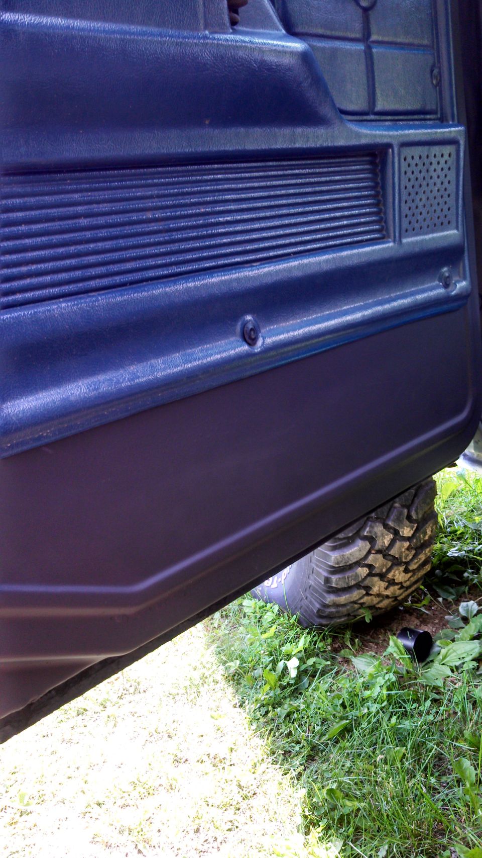 Dark blue interior door panel with a large off-road tire visible below
