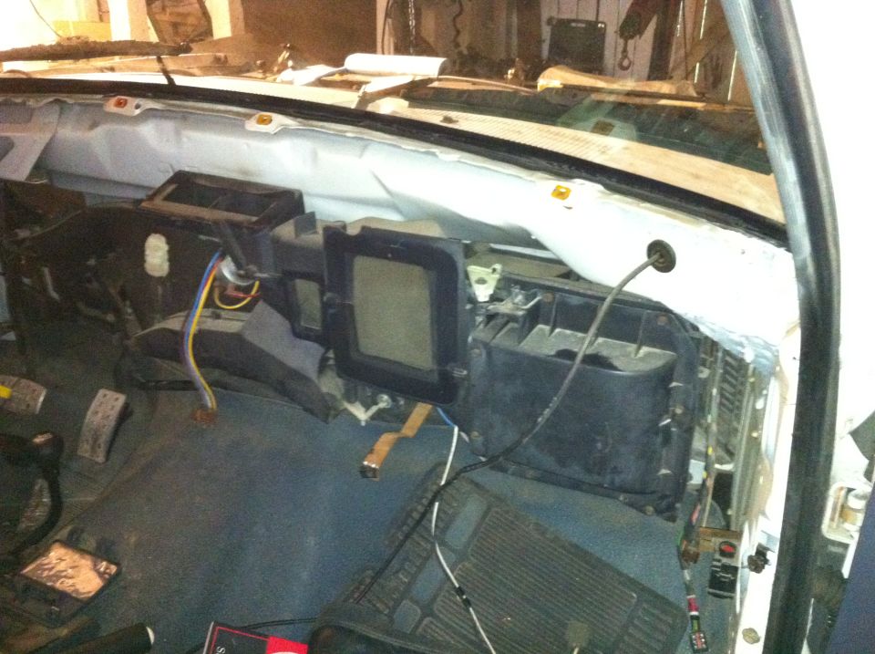 Interior of a vehicle with the dashboard removed, showing exposed wiring and HVAC components