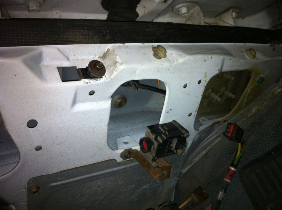 Interior of a vehicle door panel showing wiring harness, connectors, and mounting brackets
